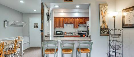 Una cocina con armarios de madera, una isla central y una zona de comedor con sillas de madera.