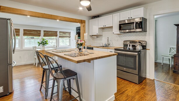 A modern kitchen with a central island, bar stools, a refrigerator, microwave, oven, and a ceiling fan. - < 1 Mi to Sand! Updated Cottage w/ Yard in Niantic (Niantic)