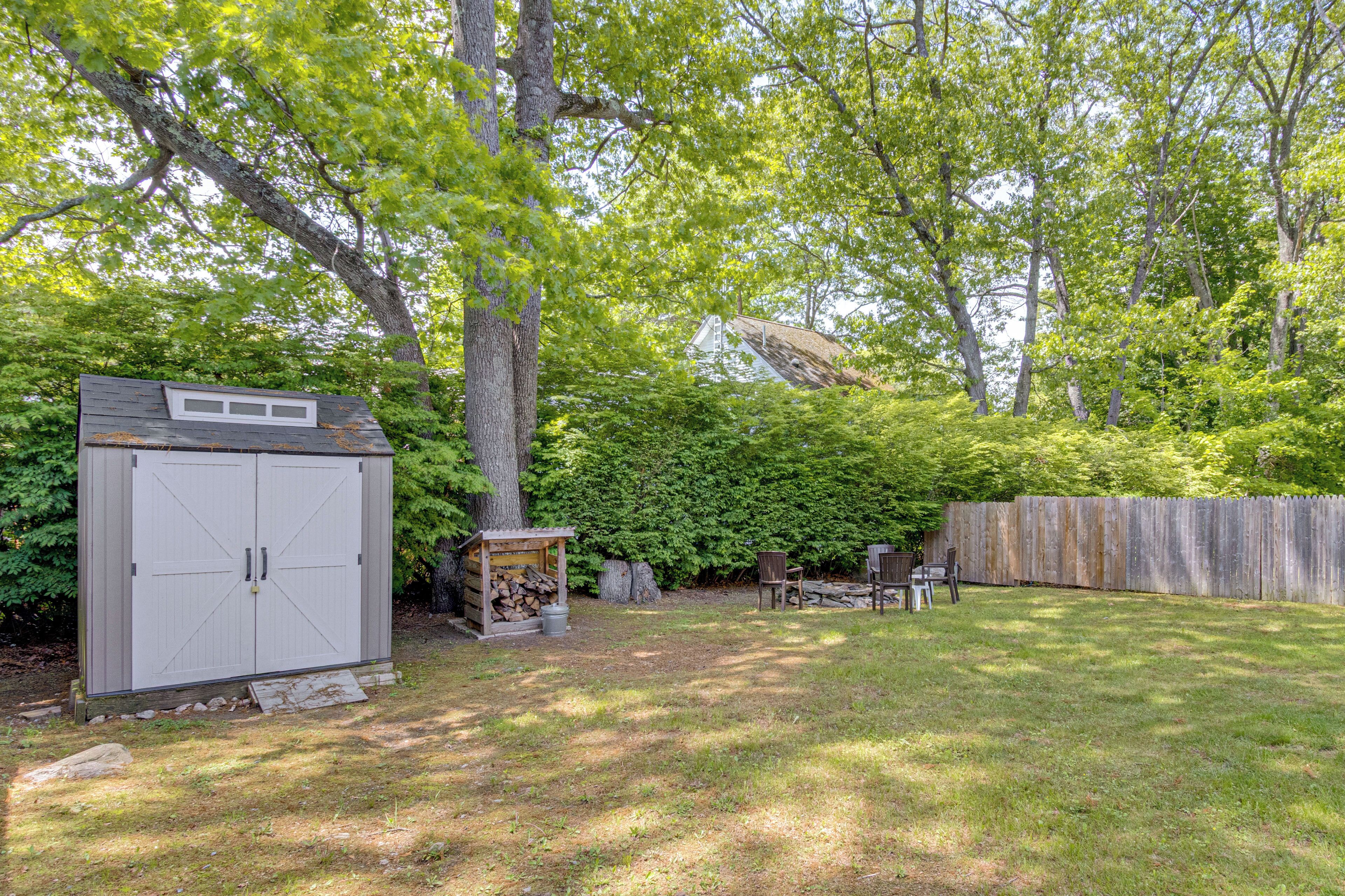 A backyard with a shed, a small wooden structure, and a wooden fence.