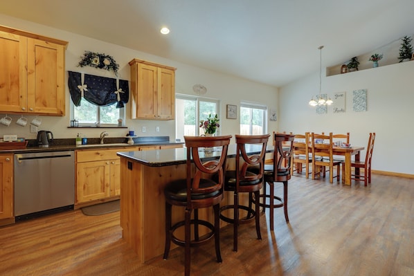 A kitchen with wooden cabinets, a bar area, and a dining table with chairs. - Mtn Views! Canon City Duplex Near Town & Riverwalk (Canon City)