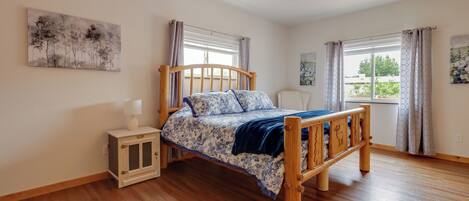 A bedroom with a wooden bed, a nightstand, a ceiling fan, and two windows with curtains.