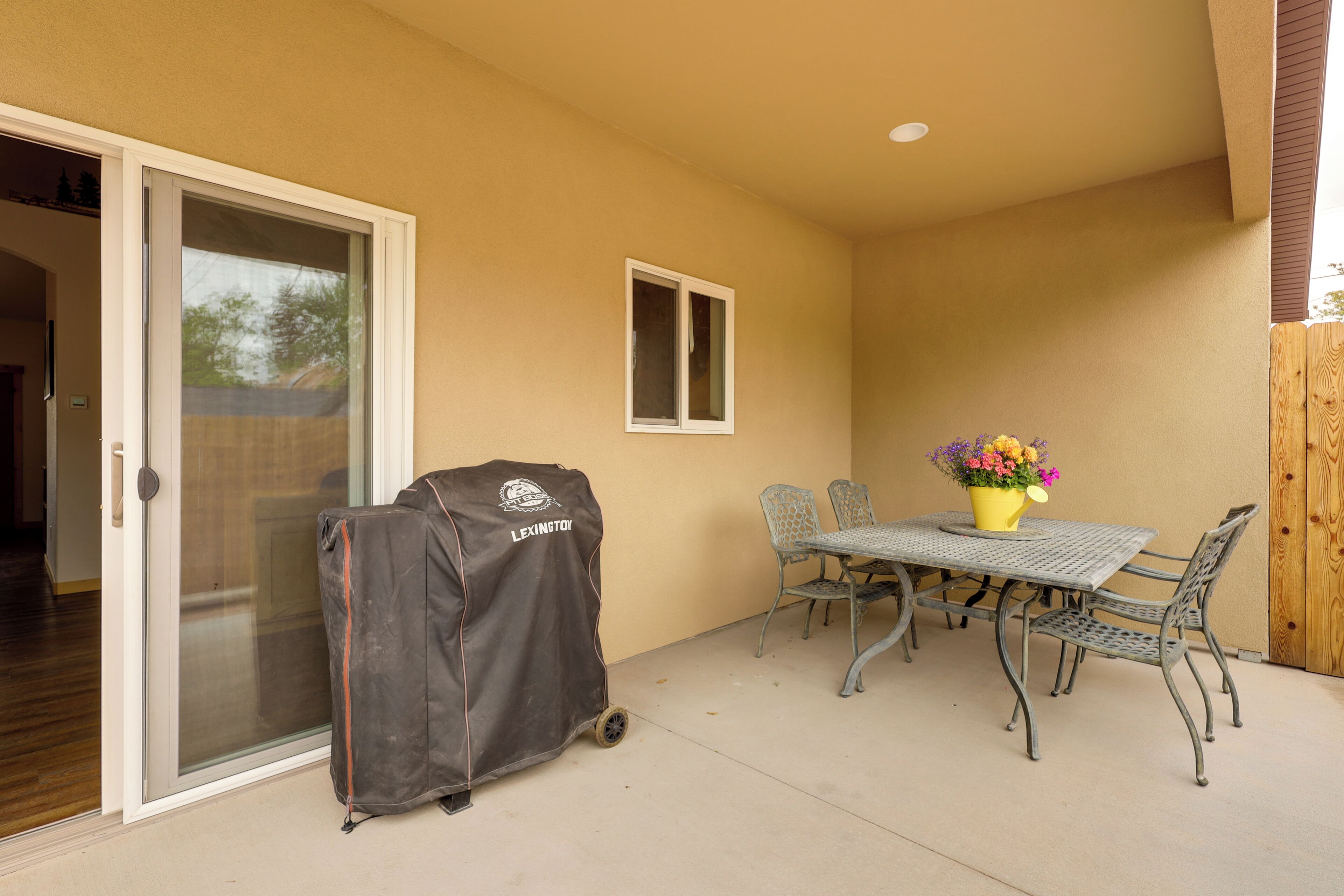 A patio with a covered grill, a table with chairs, and a potted plant.