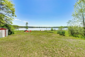 A grassy area with a lake, a shed, and some trees.