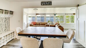 Un comedor con una mesa larga, sillas, un sofá y vistas al lago.