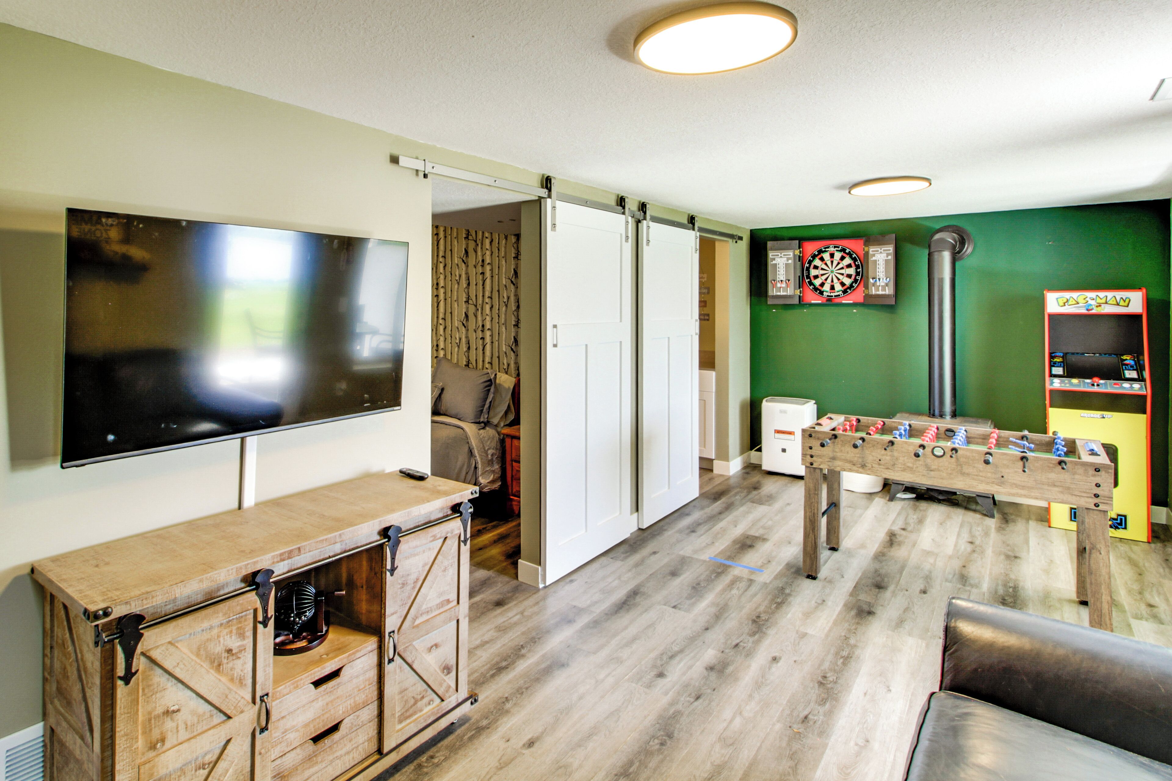 Una habitación con mesa de fútbol, dardos y televisor montado en la pared.