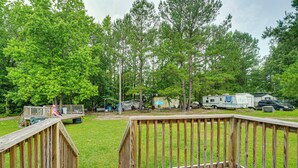 A wooden deck with a ramp leading to a grassy area, surrounded by trees and RVs. - Golf, Beaches & More! Pet-friendly Home in Leland (Leland)