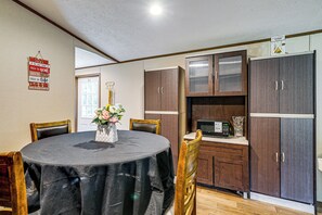 A dining area with a round table, chairs, a flower vase, and wooden cabinets. - Golf, Beaches & More! Pet-friendly Home in Leland (Leland)