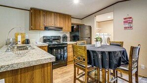 A kitchen with wooden cabinets, a stainless steel refrigerator, an oven, and a dining area with a table and chairs. - Golf, Beaches & More! Pet-friendly Home in Leland (Leland)