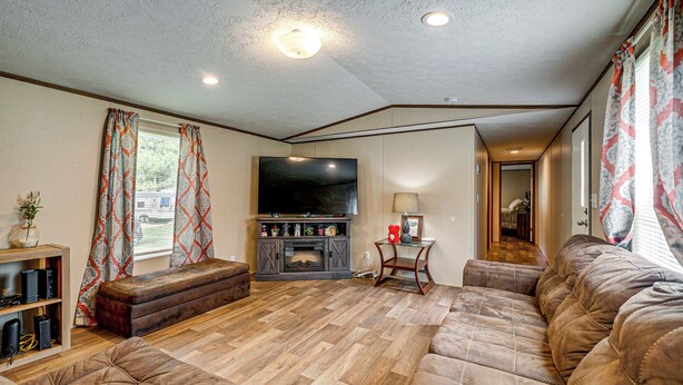 A living room with a large flat-screen TV, a fireplace, a sofa, and a wooden floor. - Golf, Beaches & More! Pet-friendly Home in Leland (Leland)