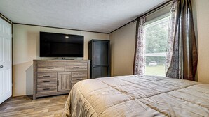 A bedroom with a bed, a television on the wall, a wardrobe, and a window with curtains. - Golf, Beaches & More! Pet-friendly Home in Leland (Leland)