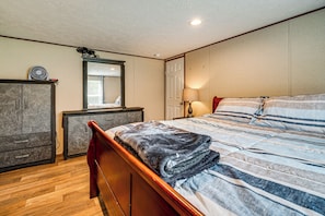 Une chambre à coucher avec un lit en bois, une table de chevet, une commode, un miroir et une lampe.