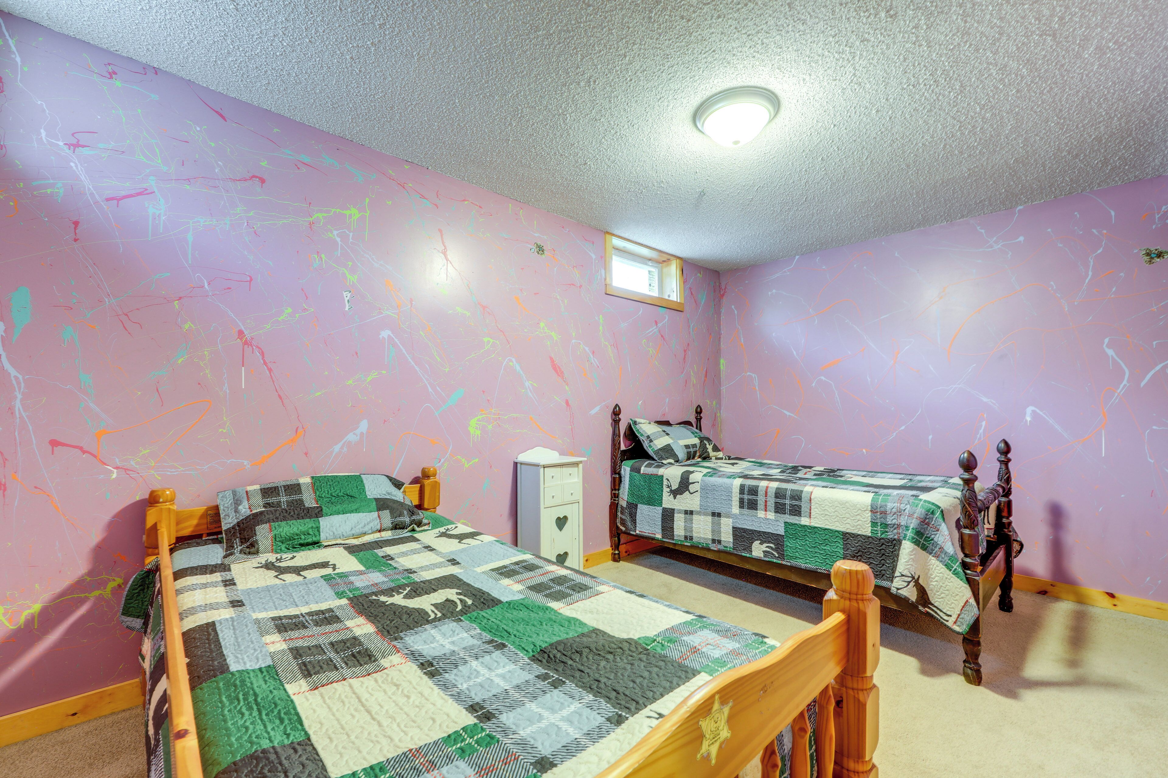 A bedroom with two beds, a window, and a ceiling light.