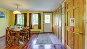 A dining area with a wooden table, chairs, a hanging light fixture, and a door with a fire safety sign. - 12 Mi to Old Forge Pond! Group Basecamp w/ Grill (Forestport)