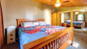 A bedroom with a wooden bed, a nightstand, a ceiling fan, and a mirror. - 12 Mi to Old Forge Pond! Group Basecamp w/ Grill (Forestport)