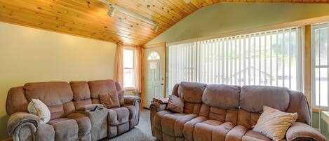 A room with two brown sofas, a ceiling fan, and a window with blinds.