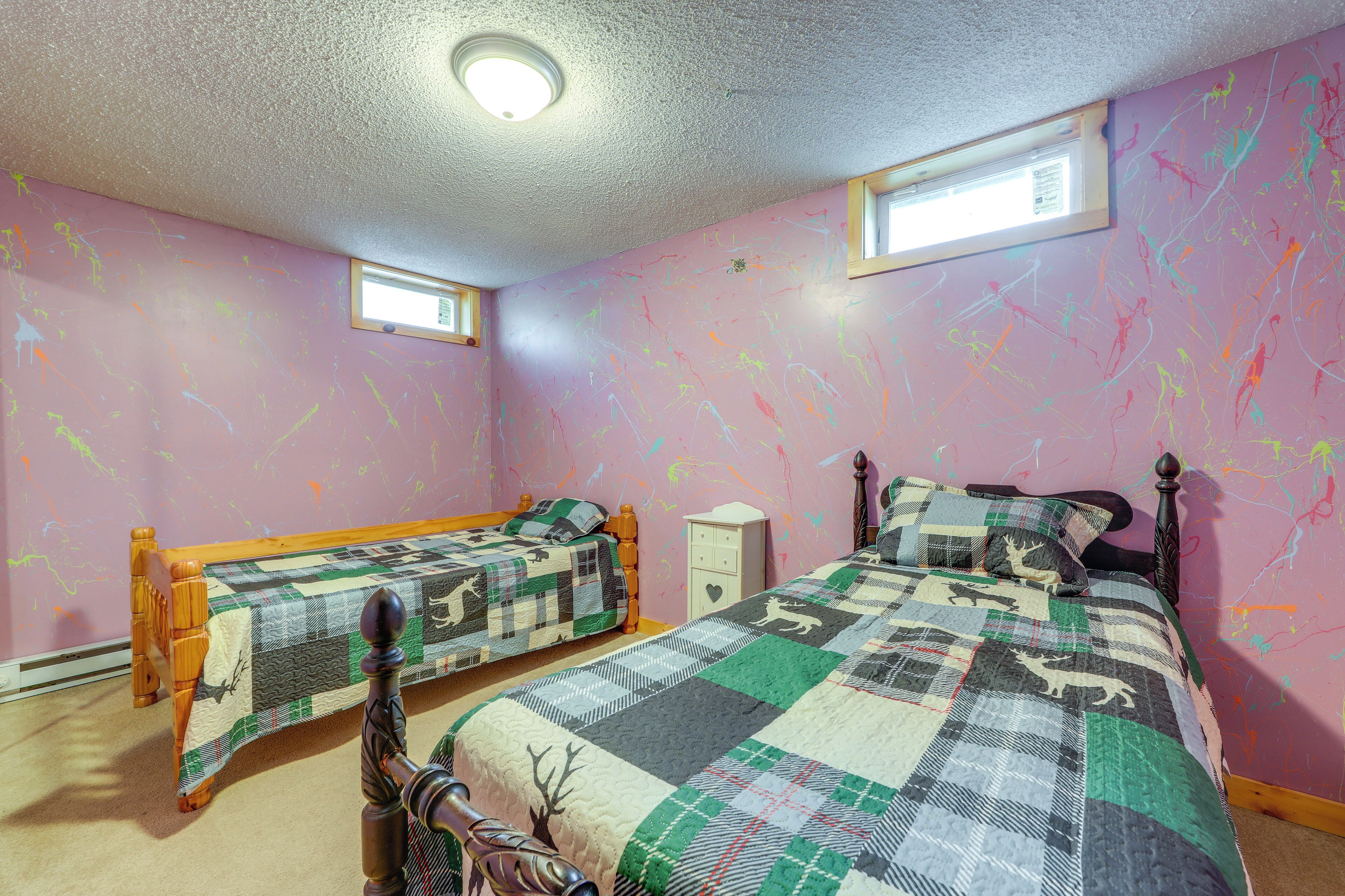 A bedroom with two beds, a nightstand, and a window.