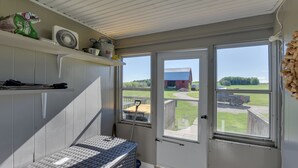 Ein Zimmer mit großem Fenster, Ventilator und einem Korbwäschesystem.