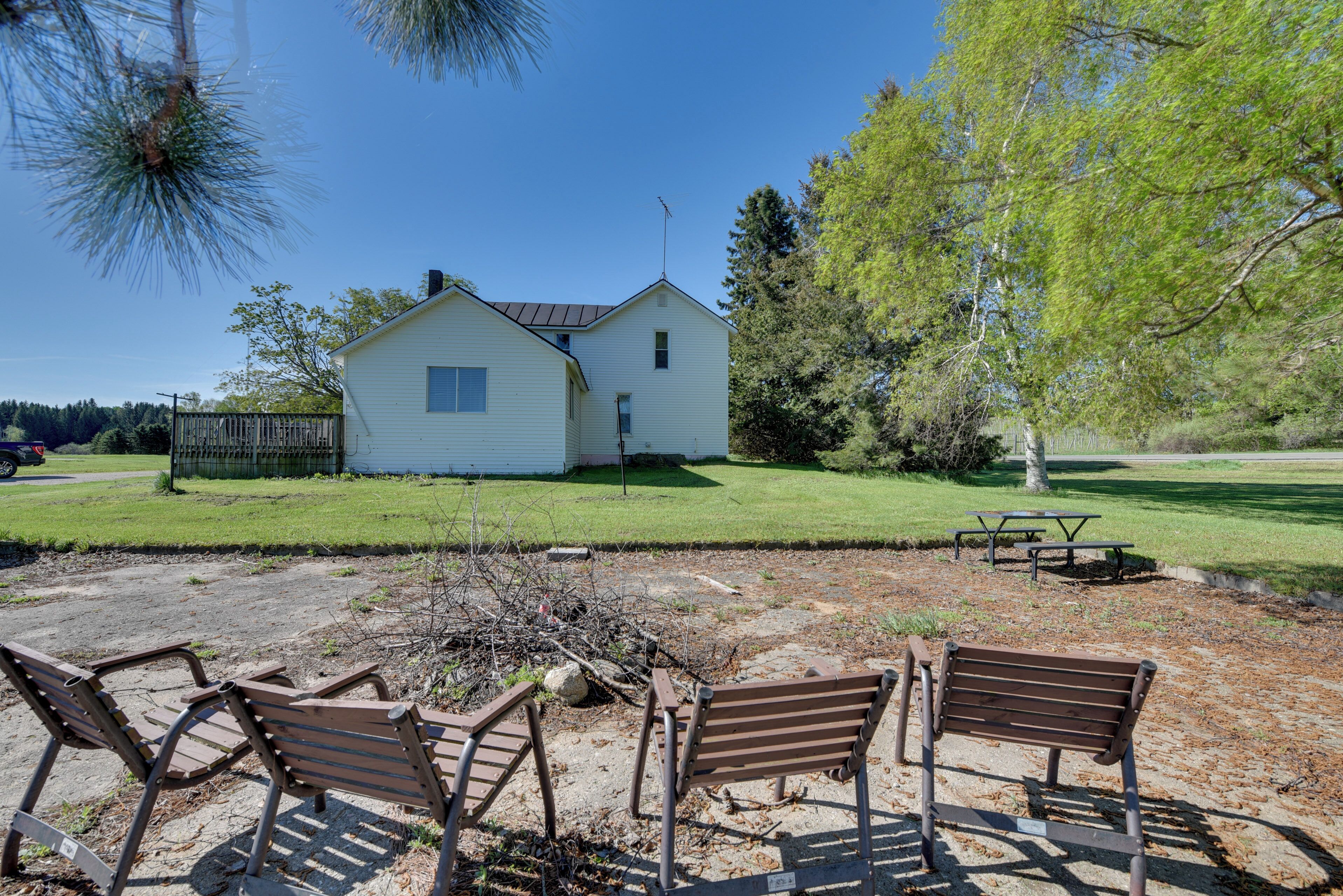 Una casa con patio, mesa de picnic y cuatro bancos.