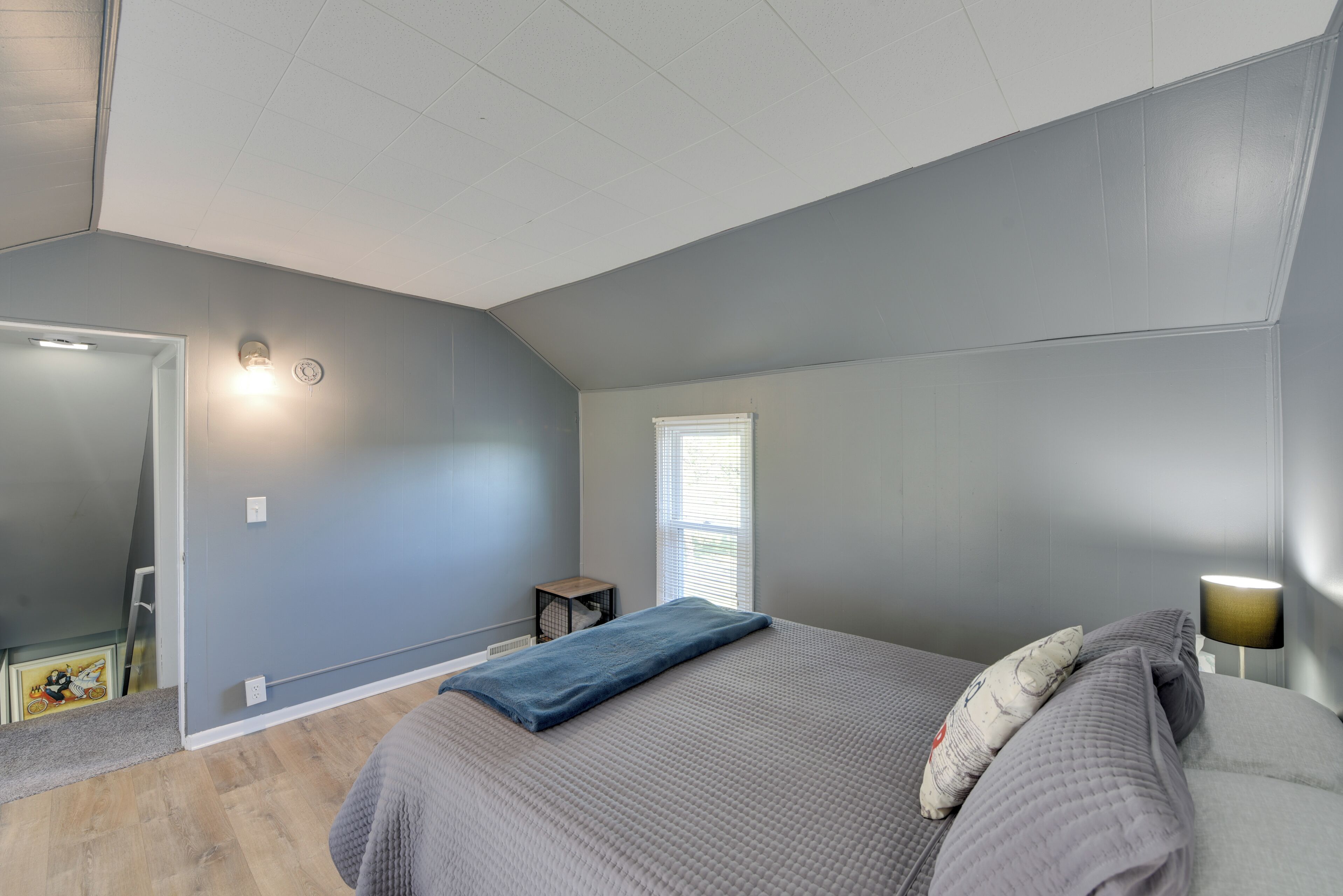 Ein Schlafzimmer mit Bett, Nachttischlampe, Fenster und Tür.