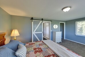 A bedroom with a bed, a nightstand, a lamp, a dresser, a mirror, and a window. - 3 Miles to Torch Lake! Farmhouse w/ Vineyard View (Central Lake)