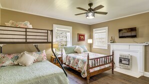 Une chambre avec un lit en bois, un ventilateur de plafond, une cheminée et un téléviseur fixé au mur.