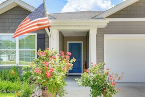 Uma casa com porta azul, uma bandeira americana e uma garagem.