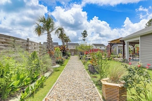 A garden pathway leading to a house with a covered patio area. - 6 Mi to Camp Lejeune! Family Home w/ Koi Pond (Jacksonville)