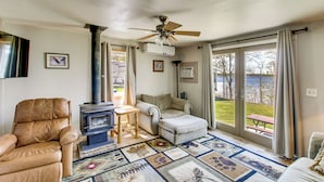 A living room with a sofa, armchair, and a fireplace. - Minnesota Lake Escape! Waterside Resort Cabin (Tenstrike)