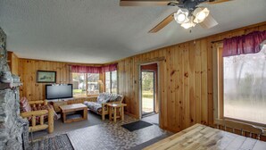 Un interior de madera con televisor, sofá y mesa de comedor.