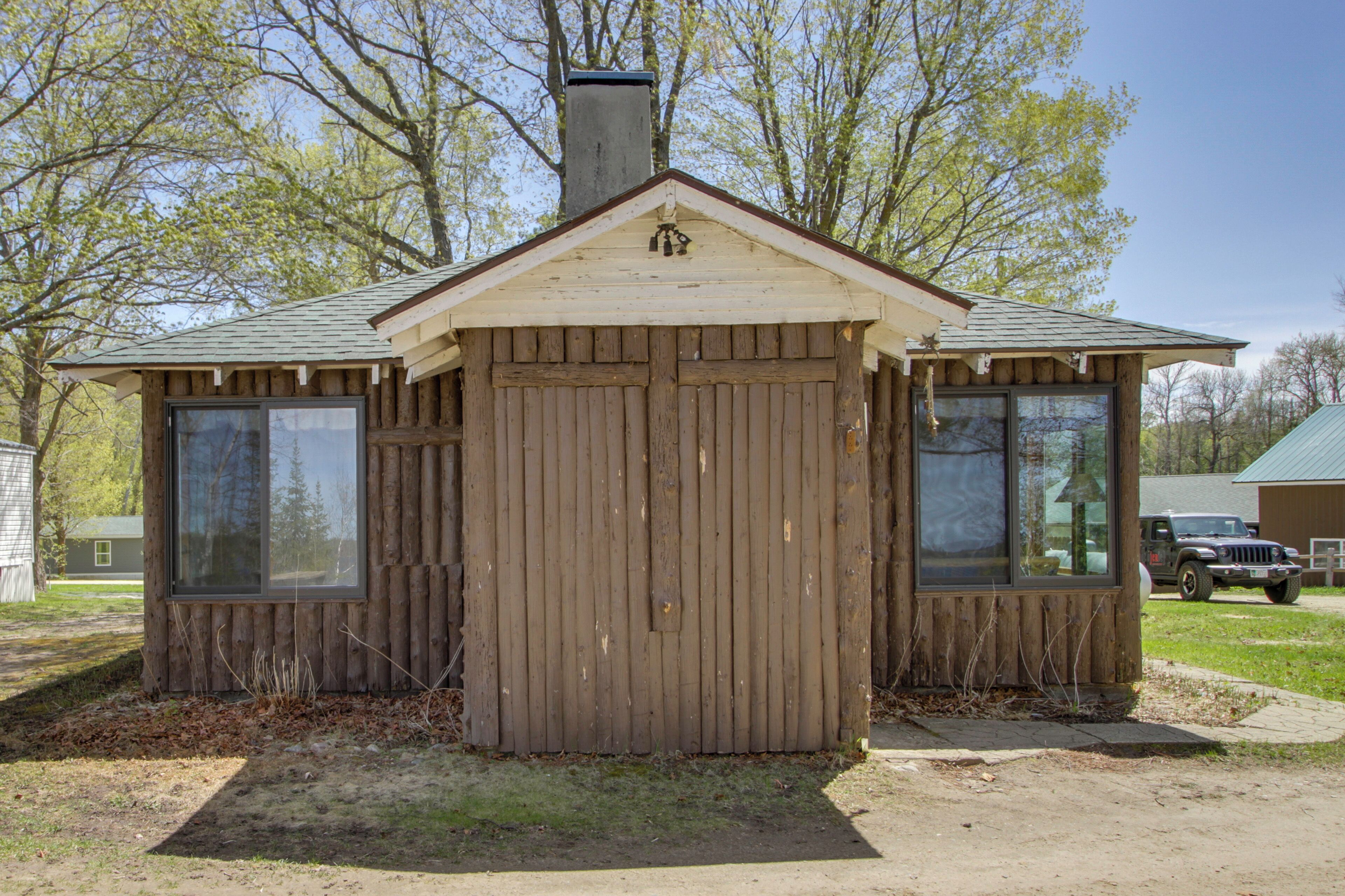 A small wooden cabin with a pitched roof, a chimney, and large windows.