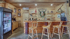 Una zona de bar rústica con muebles de madera, un refrigerador y diversas decoraciones.