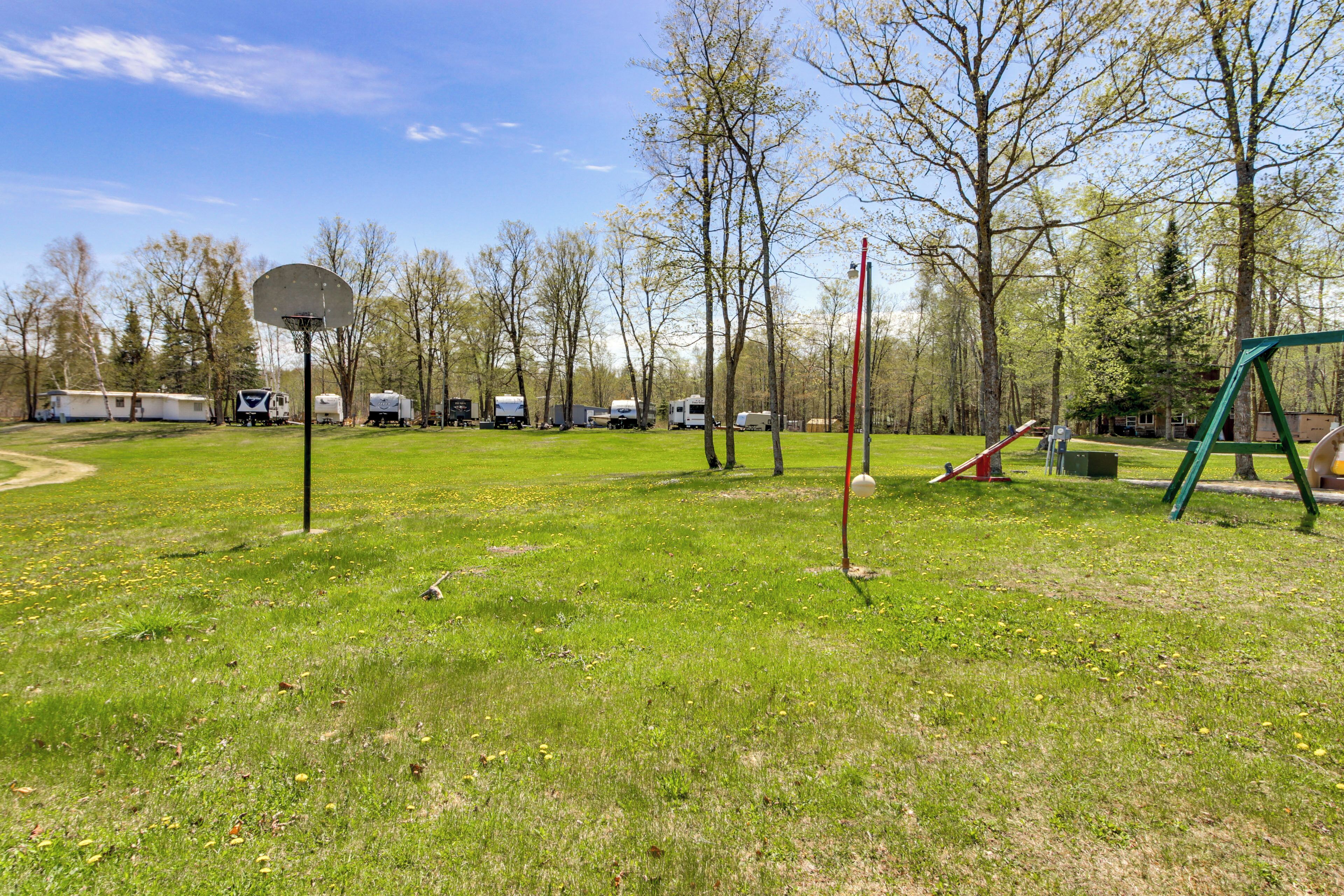 Een groen park met een basketbalveld, schommelzwaaiers en een speeltuin.