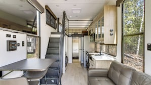A compact kitchen with a dining area and a seating space. - Steps to Gull Lake! Modern RV Stay w/ Resort Perks (Tenstrike)