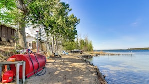 A lakeside property with a red propane tank, a wooden dock, and a house with a shed. - Steps to Gull Lake! Modern RV Stay w/ Resort Perks (Tenstrike)