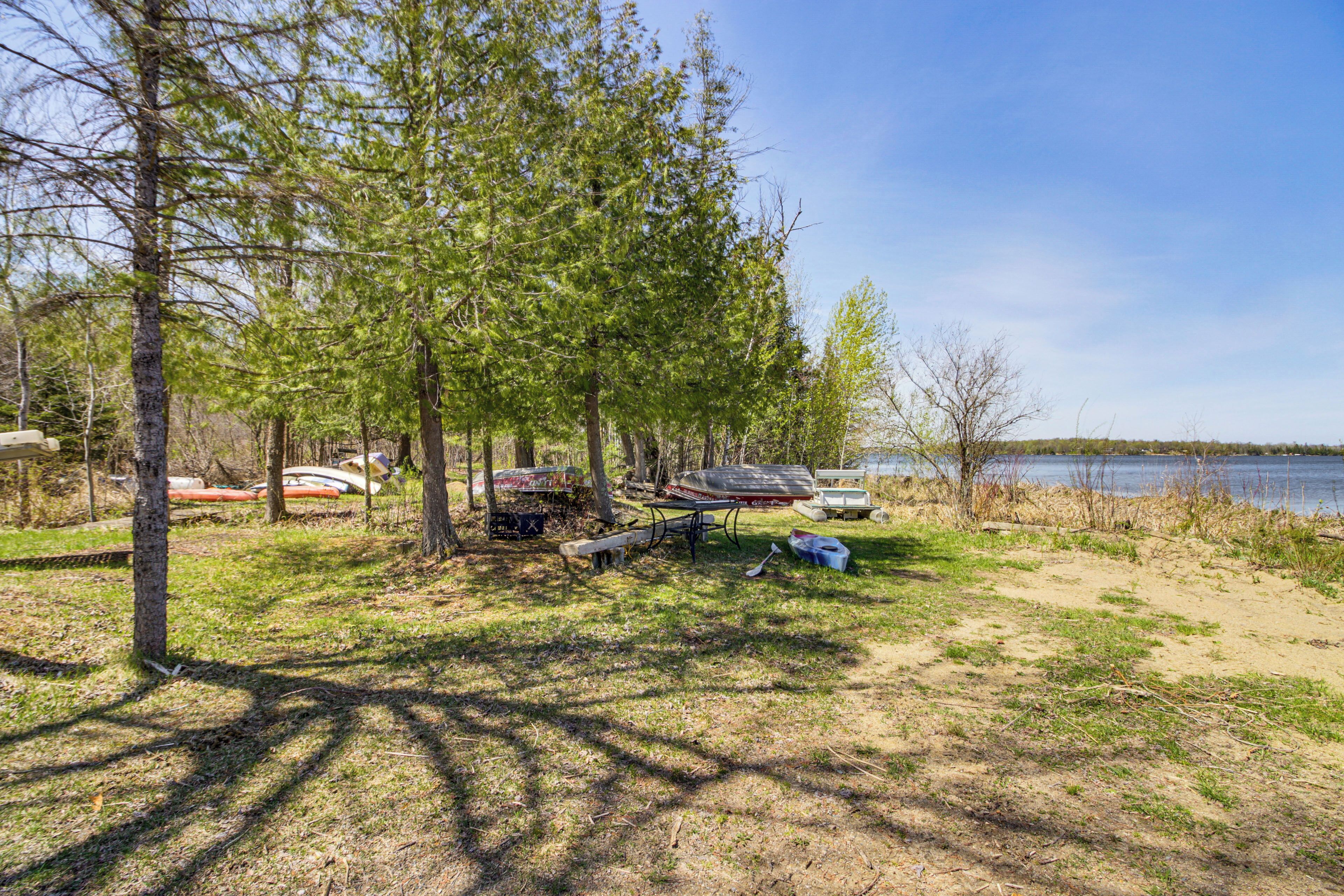 A campsite with trees, a bench, and a canoe near a lake.