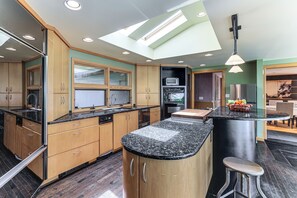 A modern kitchen with wooden cabinets, a granite countertop, and a skylight.