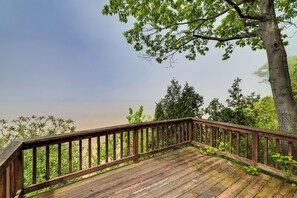 A wooden deck with a railing overlooking a forested area.