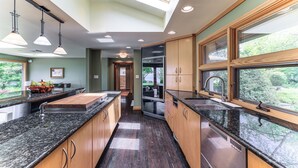 Una cocina moderna con encimeras de granito, armarios de madera, tragaluces y vistas al exterior.