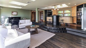 Una sala de estar moderna con chimenea, una cocina con isla negra y un comedor con taburetes de bar.
