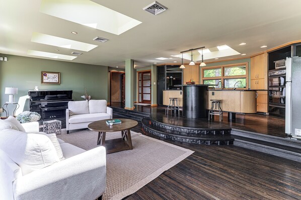 A modern living room with a fireplace, a kitchen with a bar area, and a dining space.
