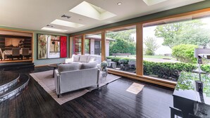 Una sala de estar moderna con chimenea, ventanas grandes y vistas al exterior.