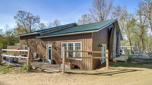 A rustic barn-style building with a green roof, a front door, and a small porch area. - Sandy Beach & Boat Dock! Gull Lake Resort Cabin (Tenstrike)