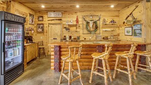 A rustic bar area with wooden stools, a refrigerator stocked with beverages, and a sign indicating a grocery section. - Sandy Beach & Boat Dock! Gull Lake Resort Cabin (Tenstrike)