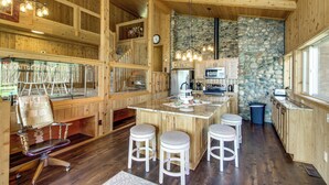 Un interior de madera con isla de cocina, taburetes de bar y una pared de piedra.