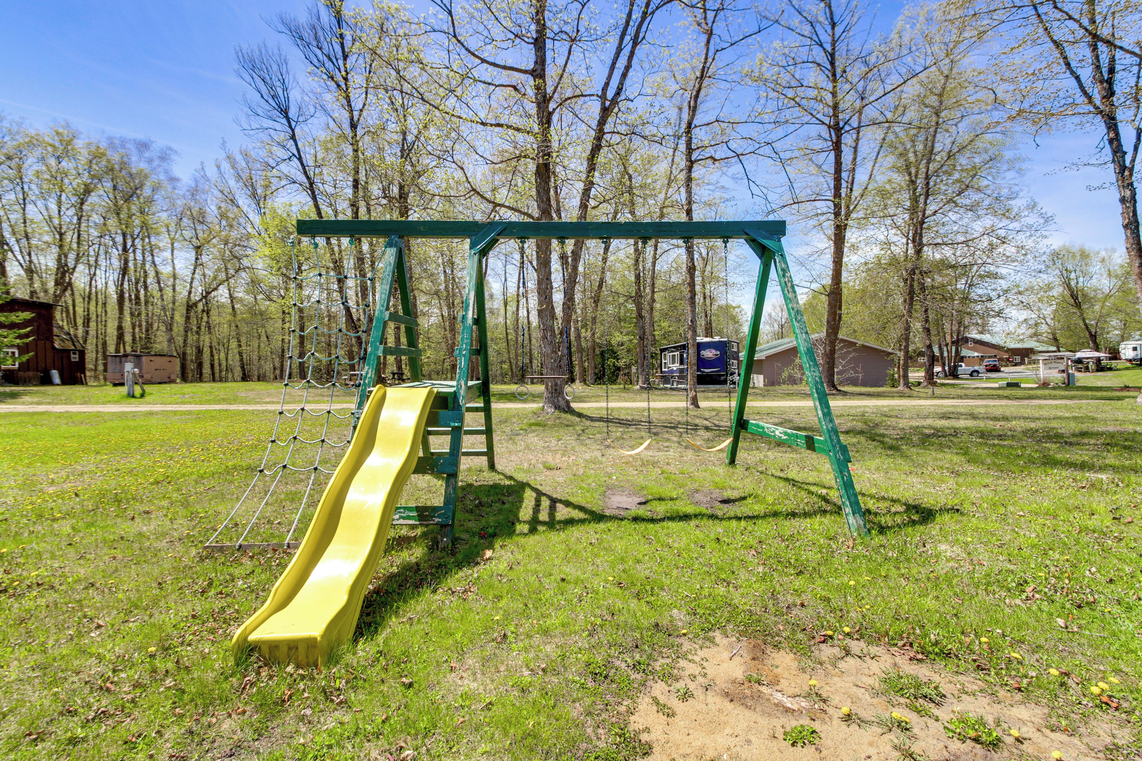 Ein Spielplatz mit Rutsche und Schaukel in einem grünen Park.