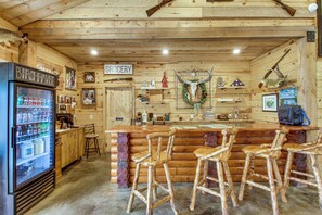 A rustic bar area with wooden furniture, a refrigerator, and a sign indicating a grocery section.