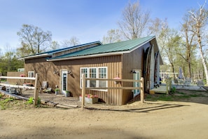 A wooden building with a green roof, a fenced entrance, and a small porch area.