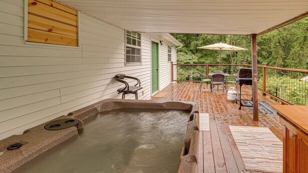A wooden deck with a hot tub, outdoor furniture, and a view of the surrounding greenery. - Walk to Town: Fayetteville Retreat w/ Hot Tub! (Fayetteville)