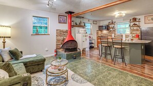 A living room with a fireplace, a kitchen with bar stools, and a dining area. - Walk to Town: Fayetteville Retreat w/ Hot Tub! (Fayetteville)