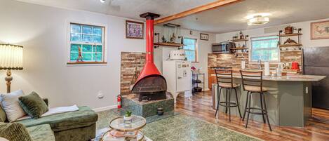 Una sala de estar con chimenea, una cocina con taburetes de bar y un comedor.